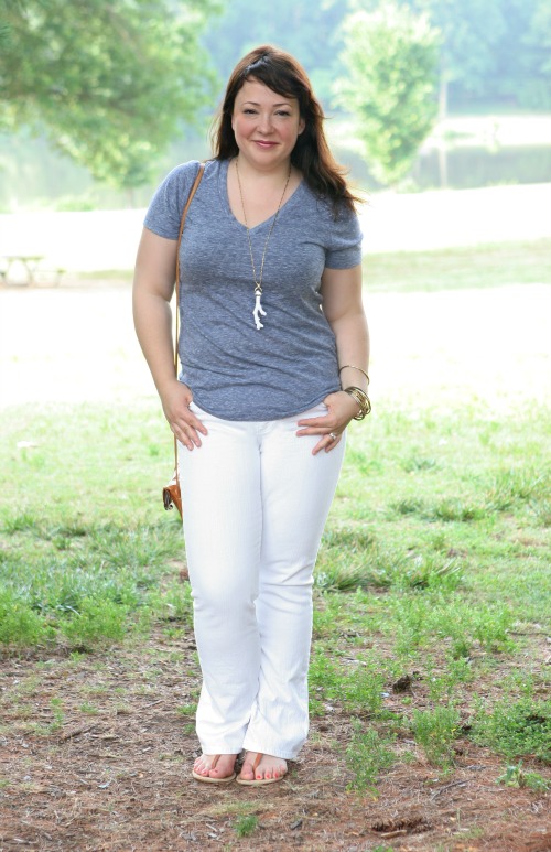 Woman in an Old Navy Vintage Tee v-neck in gray-blue with white bootcut jeans and a Stella and Dot coral pendant necklace