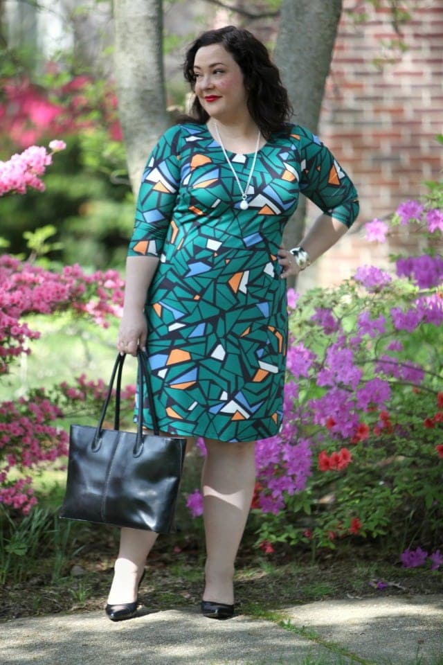 woman in a mosaic print green sheath dress in a garden