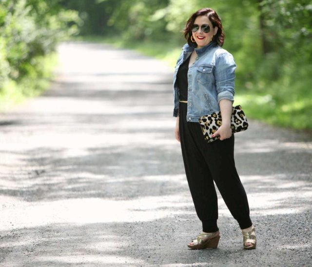 Wardrobe Oxygen wearing a Loveappella jumpsuit, J. Crew Factory denim jacket, and Love,Cortnie clutch bag