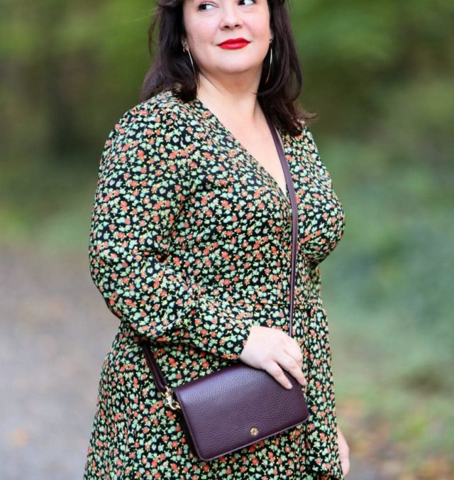 Wardrobe Oxygen in a petite black leather Moto jacket with a floral wrap dress, black heeled knee-high wide calf boots, and the Dagne Dover Small Andra Crossbody in Oxblood #dagnedover