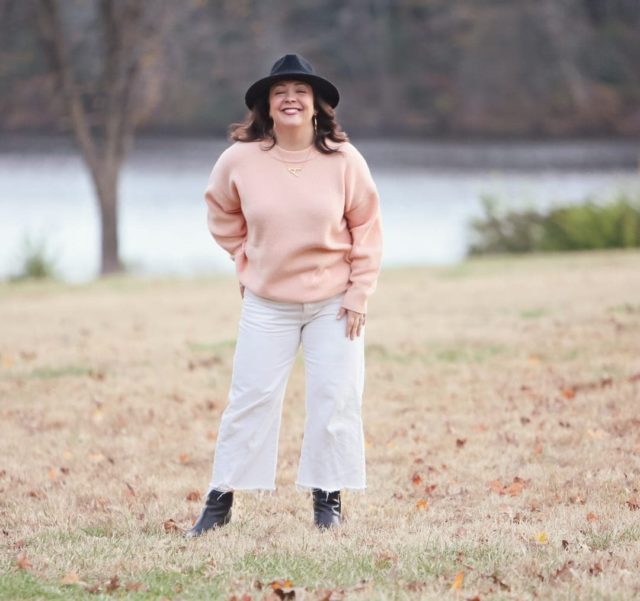 Wardrobe Oxygen in the And Comfort Fika sweater in peach with cream wide leg cropped jeans from Universal Standard, a black felt fedora from Ann Taylor, gold Faye Knocker hoop earrings from Jenny Bird, and black Clarks ankle booties