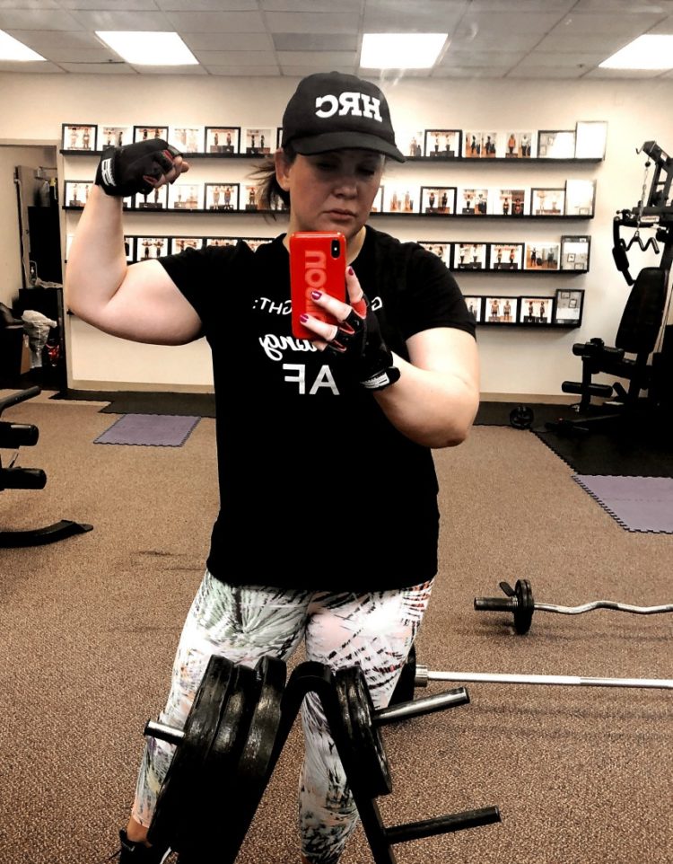 woman taking mirror selfie with one arm flexed to show her biceps