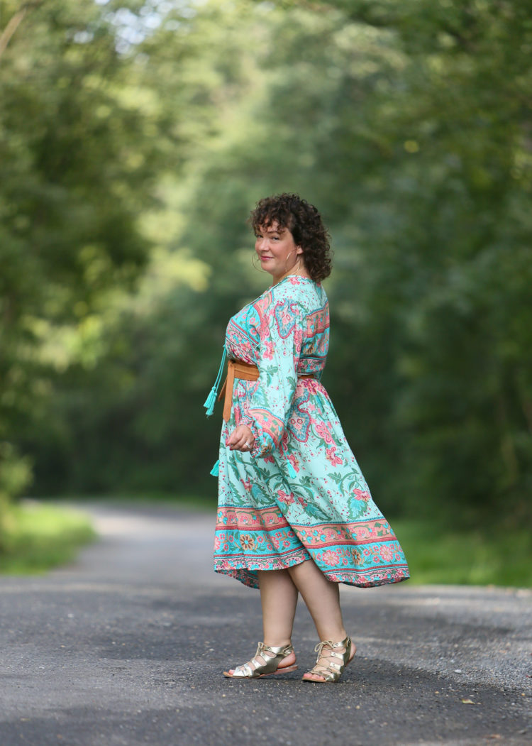 woman in green and pink floral dress walking away from the camera but looking back