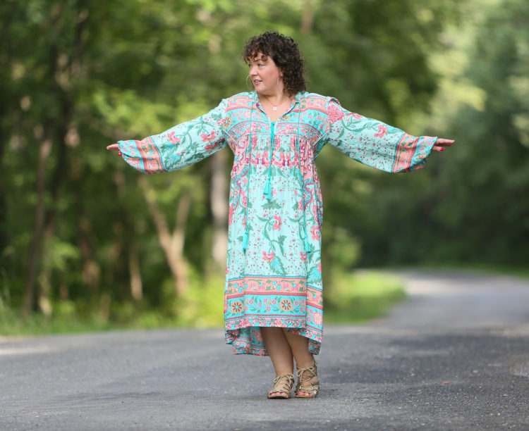 woman in oversized light green dress with her arms up to show the size