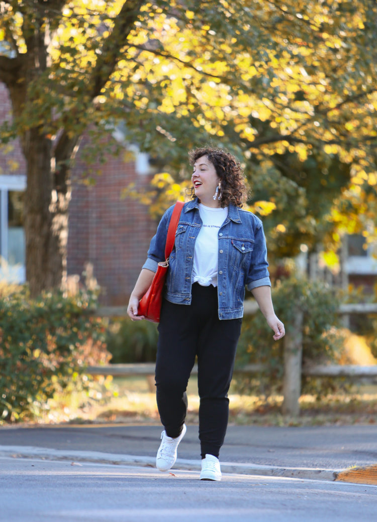 woman in a denim jacket and black knit joggers crossing the street