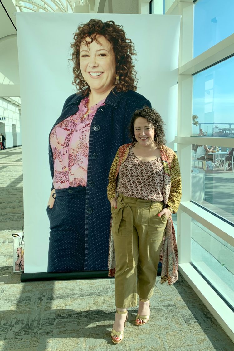 Alison Gary of Wardrobe Oxygen at cabi Scoop conference in San Diego. She is wearing a cabi Spring 2020 outfit and standing in front of a billboard of herself in the cabi campaign for that season.