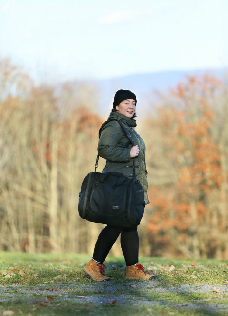 An over 40 woman carrying the Tom Bihn Aeronaut 45 with the shoulder strap.