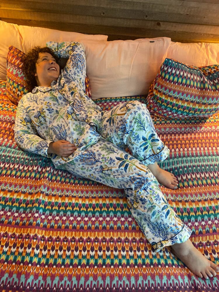 Alison lying on her bed laughing while wearing organic poplin pajamas from Printfresh