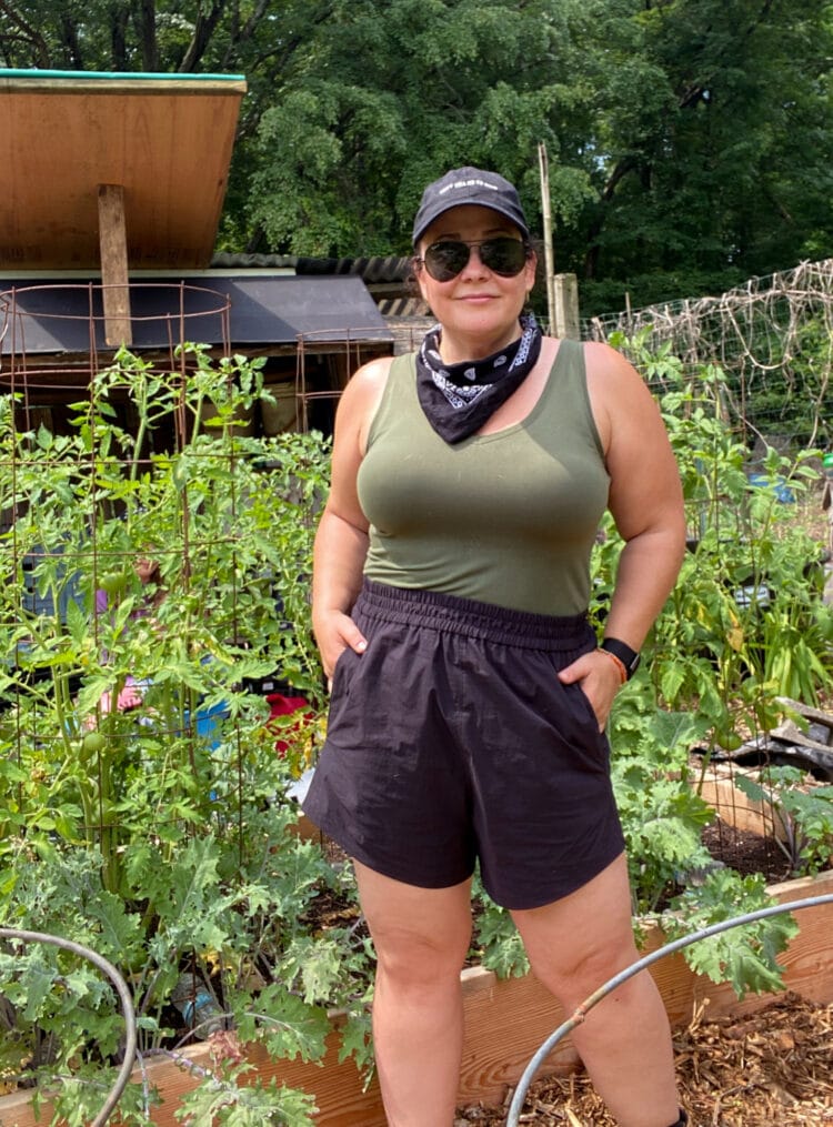 IMO the best size-inclusive active shorts are the Universal Standard Sunny Swim Shorts which I am wearing here in black with an olive fitted tank while working in my garden.