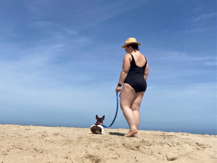 Alison and her dog on the beach walking away from the camera