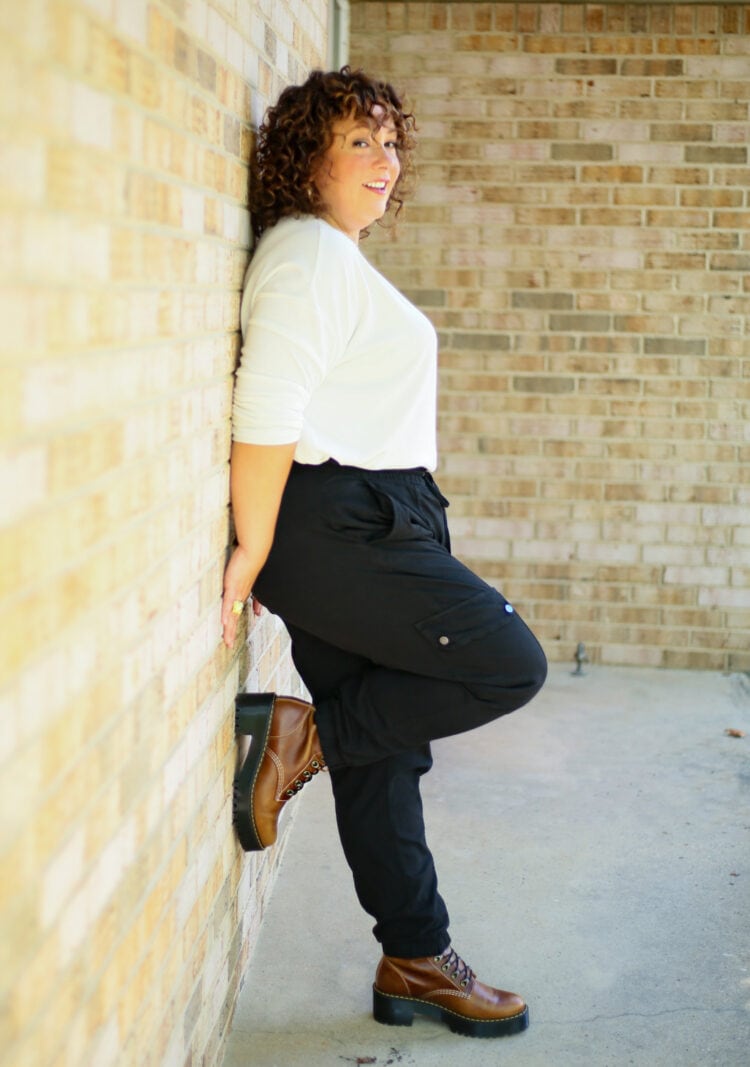 Alison of Wardrobe Oxygen leaning against a brick wall with one foot up showing her brown Doc Marten boots