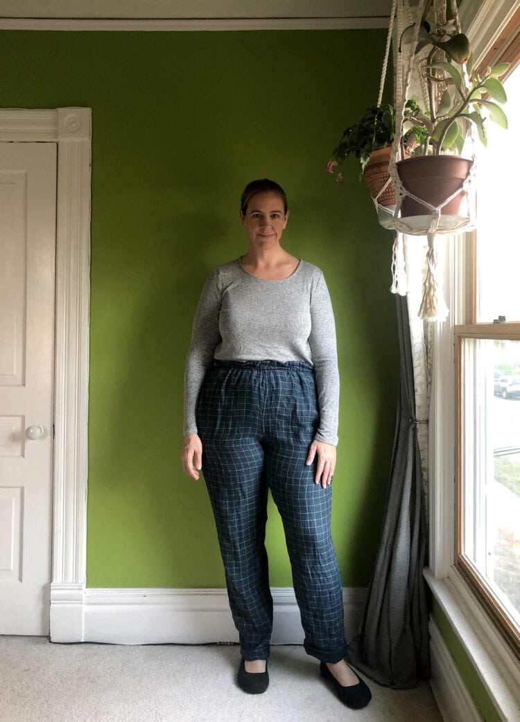 Woman in a gray long sleeved t-shirt tucked into navy check pull on pants