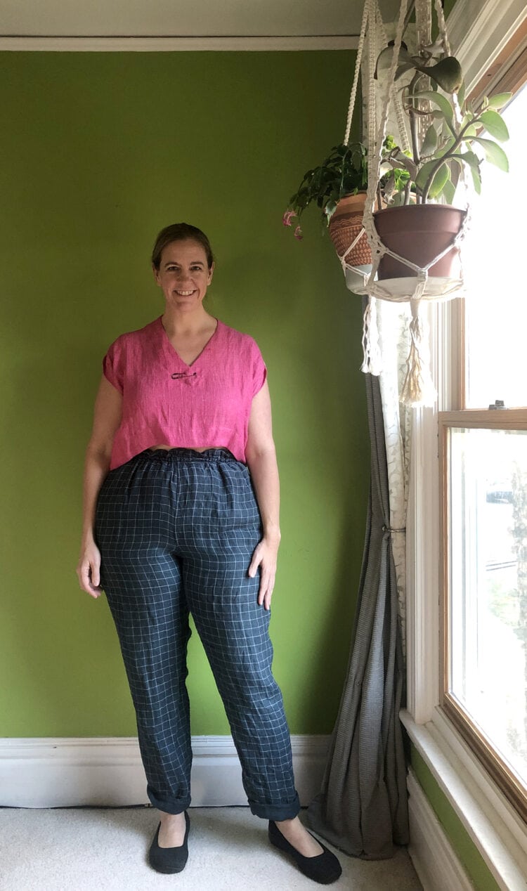 Woman in a cropped pink linen top styled with navy check ankle pants