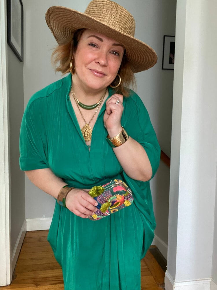 Alison wearing the green ever by X dress styled like a caftan with a straw hat and gladiator sandals