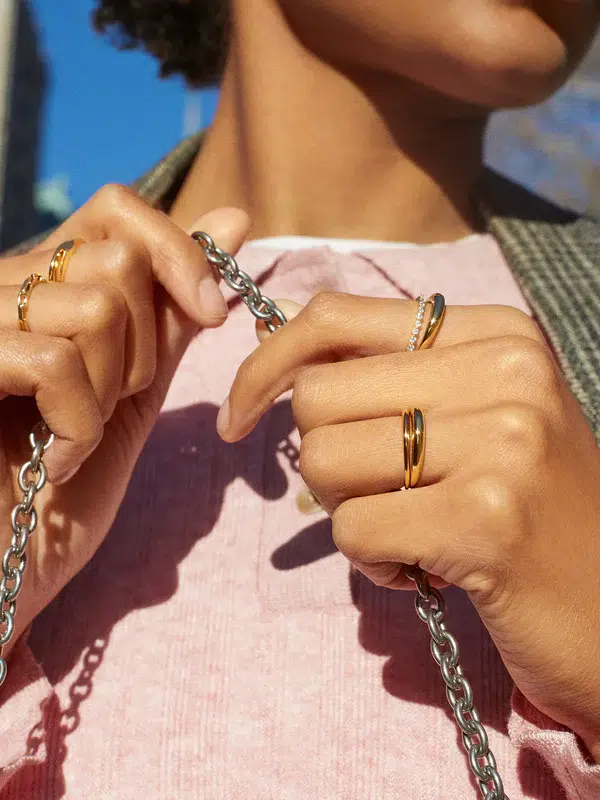 Woman wearing multiple gold and crystal stone rings from the retailer BaubleBar