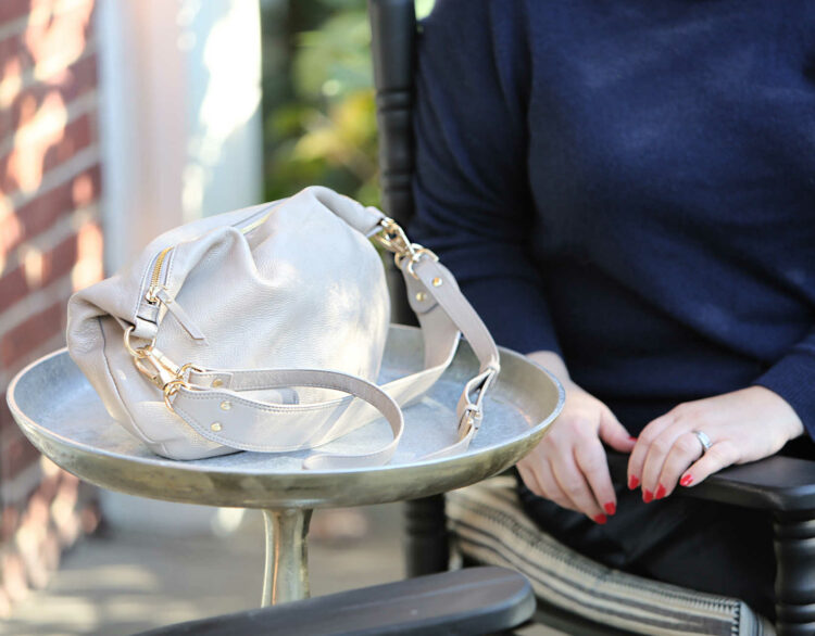 A closeup of the Quince Italian Leather Convertible Crescent Shoulder Bag in Taupe after carrying for over a month. It still looks like new and has soft leather and shiny heavyweight gold hardware.