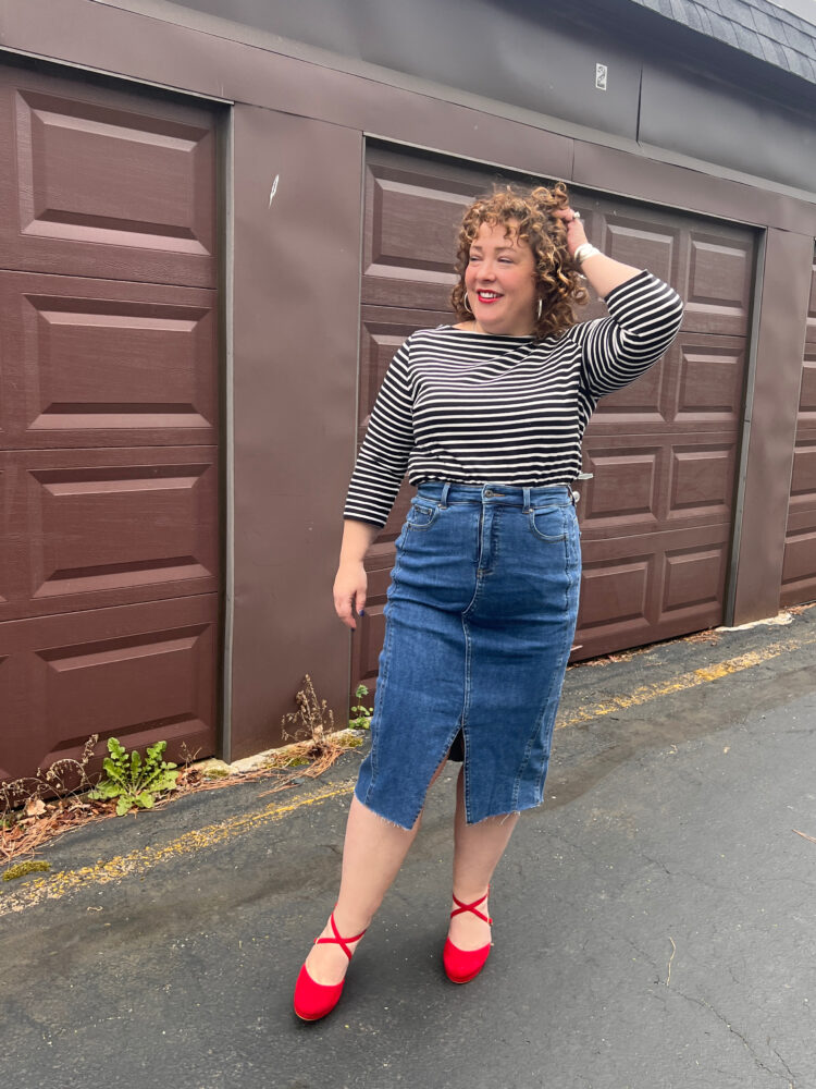 Woman wearing a black and white striped Breton with a denim skirt and red suede pumps