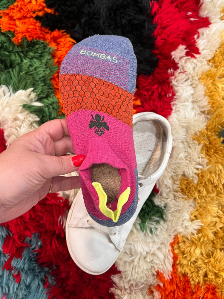 Bombas ankle sock slid over the insole of a Birkenstock Bend sneaker, the opening of the sock on the bottom back of the insole