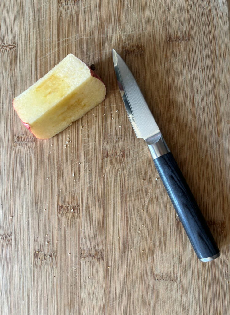 a Quince japanese knife on a cutting board with an apple core