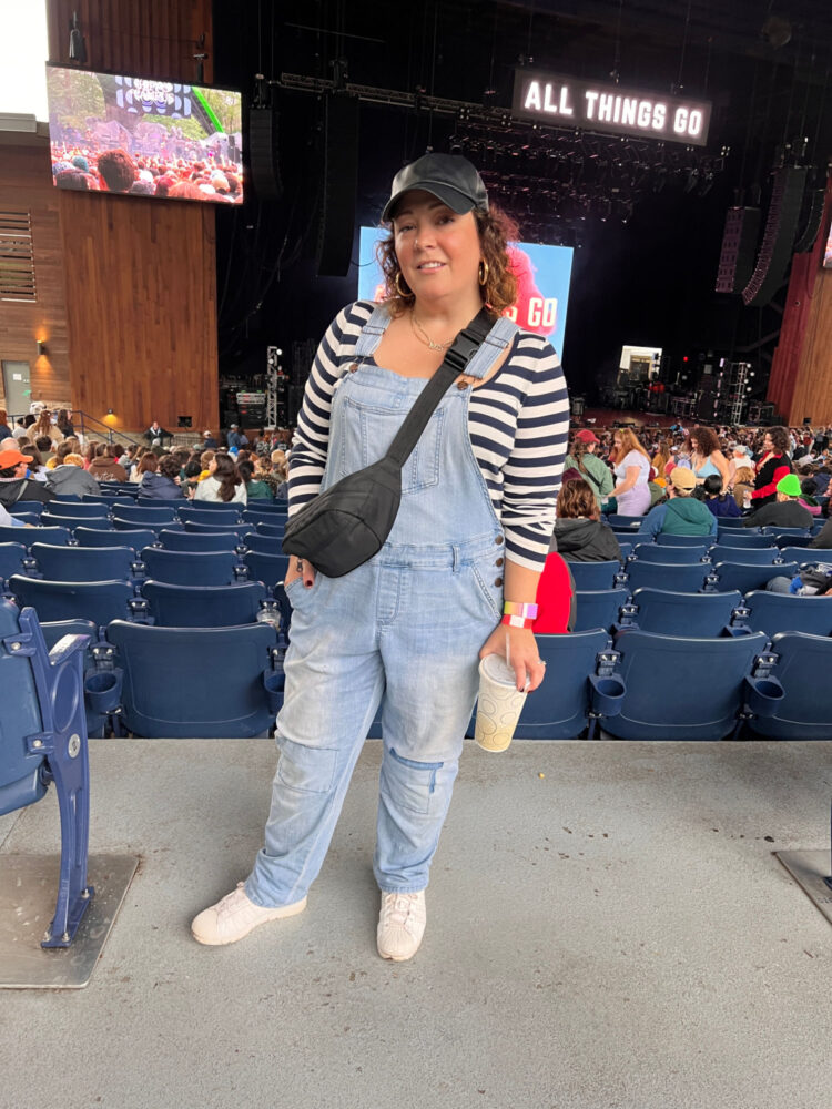 All Things Go festival Woman at the All Things Go festival wearing a striped shirt, overalls, and a belt bag as a crossbody